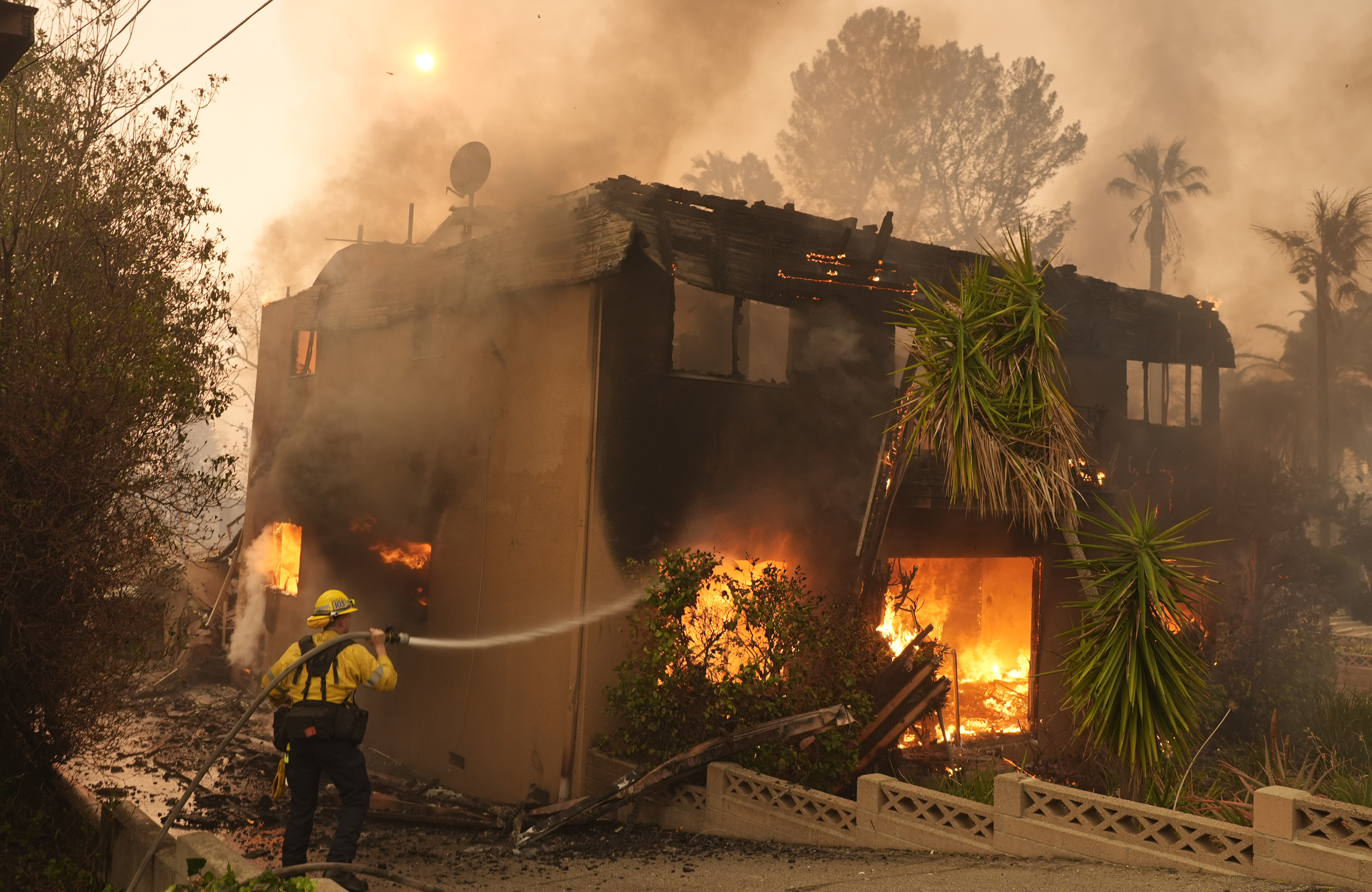 A firefighter tries to extinguish flames at a burning apartment building. A firefighter tries to extinguish flames at a burning apartment building.