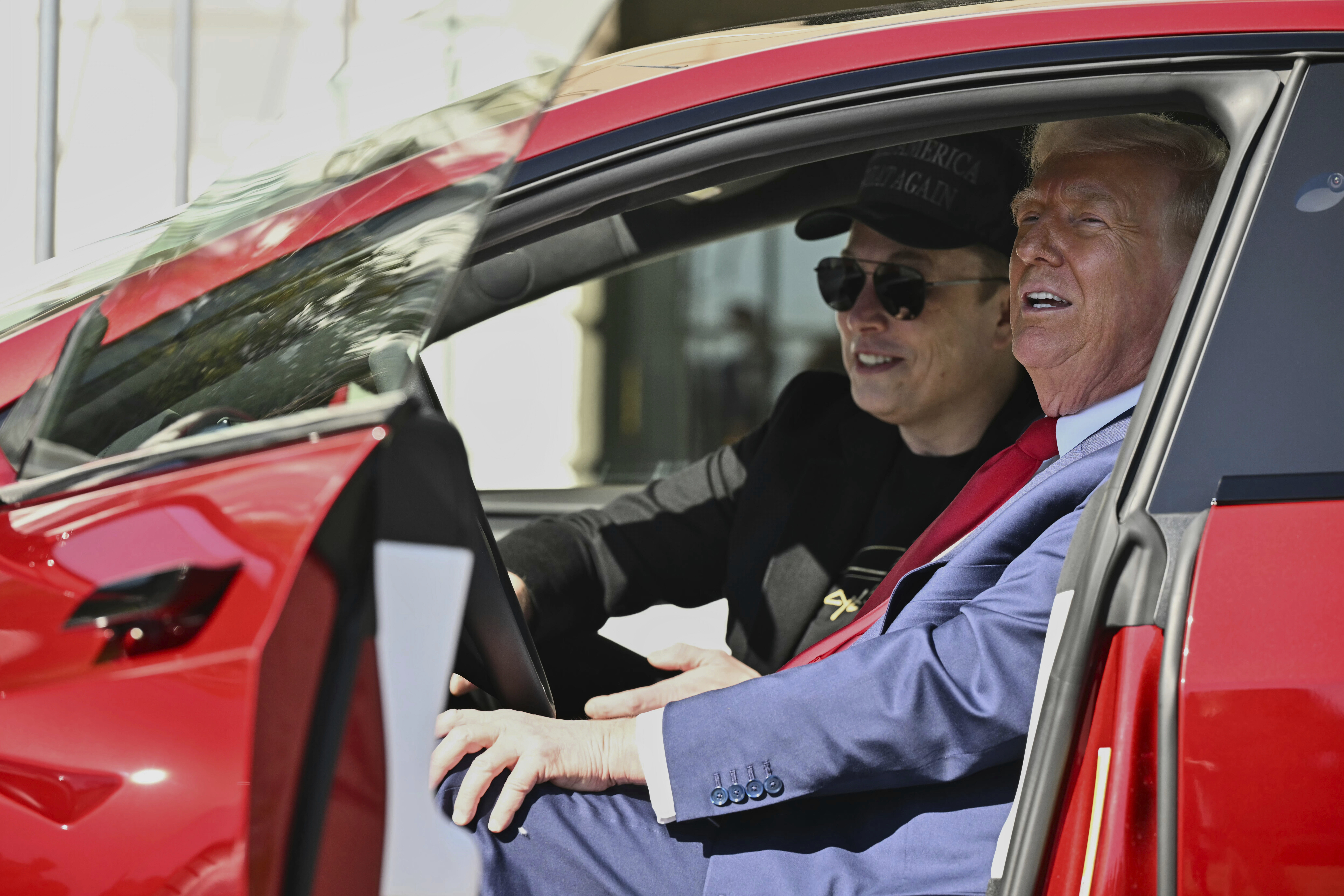 President Donald Trump and Tesla CEO Elon Musk speak to reporters as they sit in a red Model S Tesla vehicle on the South Lawn of the White House.